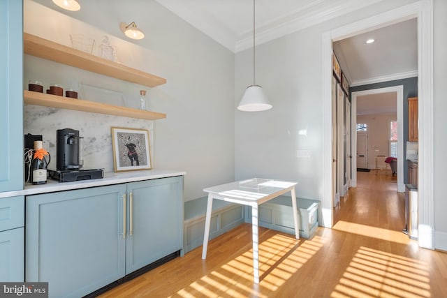 kitchen featuring pendant lighting, ornamental molding, light hardwood / wood-style floors, and blue cabinetry