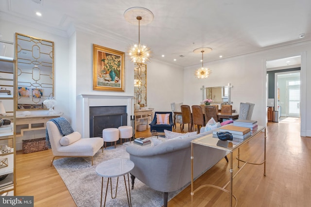 living room featuring crown molding, light hardwood / wood-style floors, and a notable chandelier