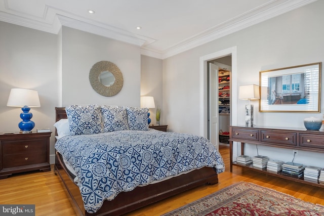 bedroom featuring crown molding, a spacious closet, light hardwood / wood-style floors, and a closet