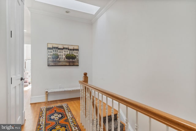 corridor with crown molding, light hardwood / wood-style flooring, and a skylight