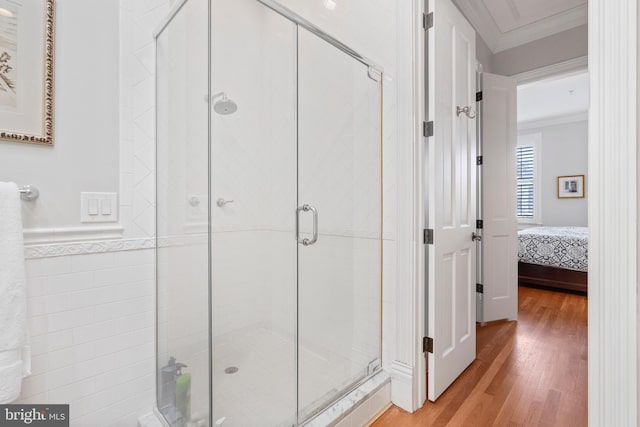 interior space with hardwood / wood-style flooring, a shower with door, and ornamental molding