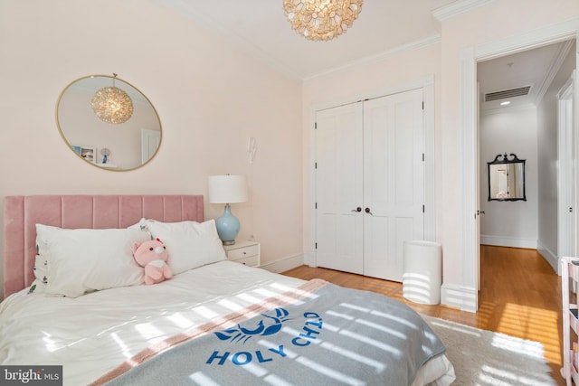 bedroom with crown molding, light wood-type flooring, and a closet