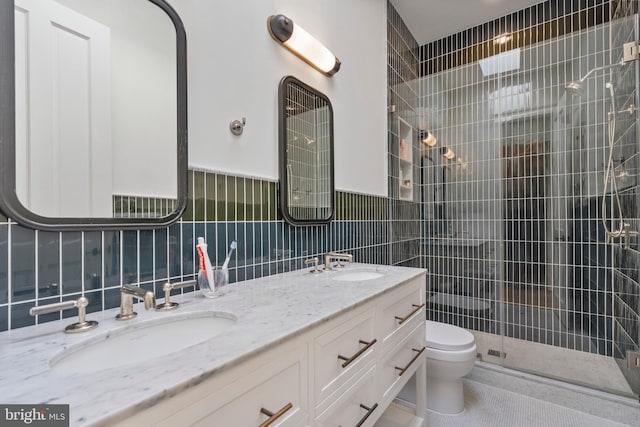 bathroom with vanity, toilet, a shower with door, and tile walls