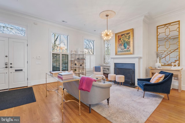 living room with crown molding, a notable chandelier, and light wood-type flooring