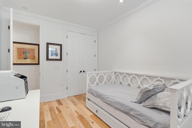 bedroom with crown molding, wood-type flooring, and a closet