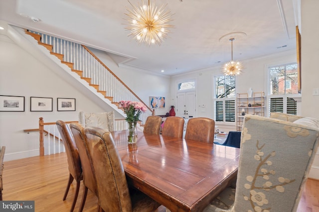 dining room with an inviting chandelier, ornamental molding, and light wood-type flooring