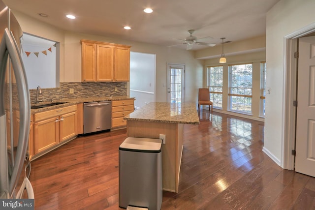 kitchen with pendant lighting, backsplash, stainless steel appliances, a kitchen island, and light brown cabinets