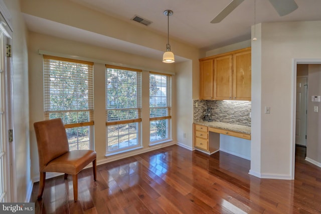 kitchen featuring built in desk, decorative light fixtures, decorative backsplash, light stone countertops, and dark wood-type flooring