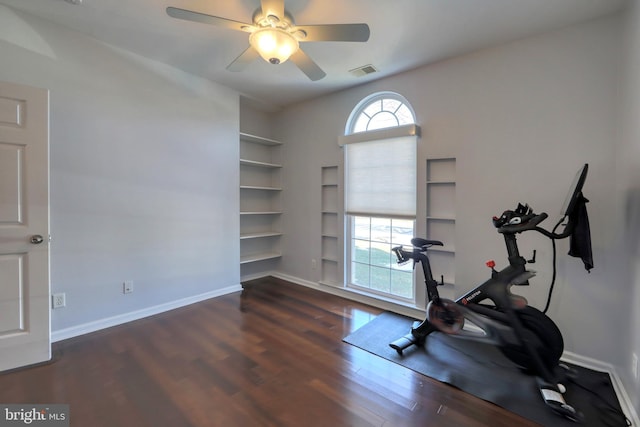 workout area with dark hardwood / wood-style flooring, ceiling fan, built in shelves, and a healthy amount of sunlight