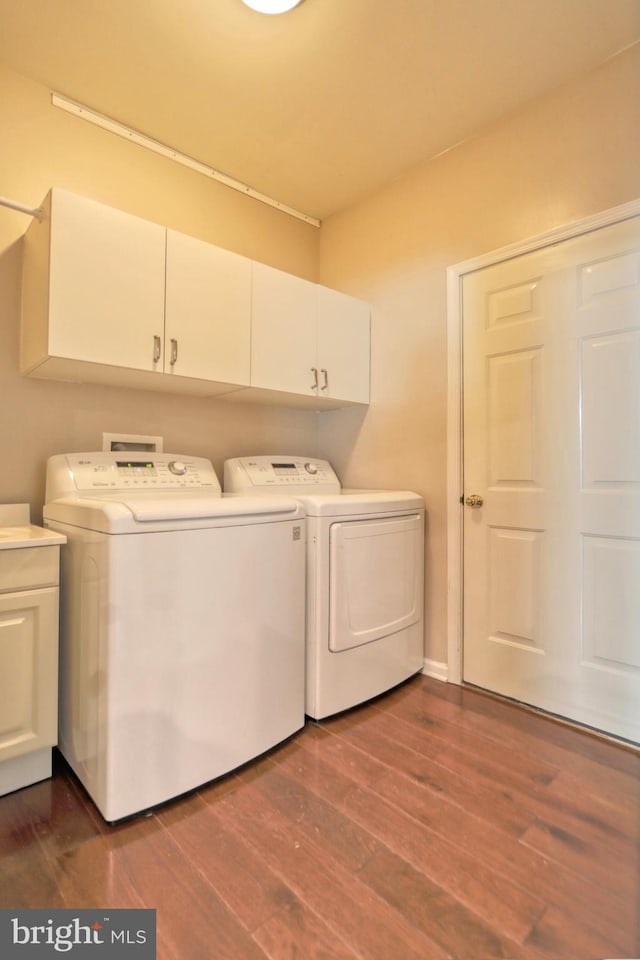 laundry room with cabinets, washing machine and dryer, and dark hardwood / wood-style floors