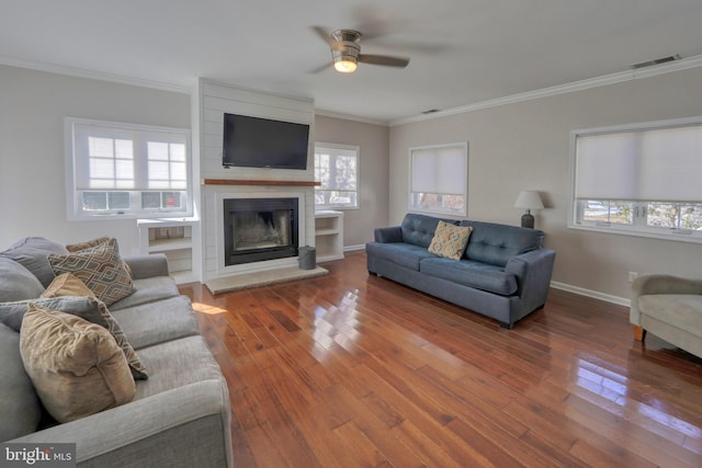 living room featuring hardwood / wood-style flooring, crown molding, a large fireplace, and ceiling fan