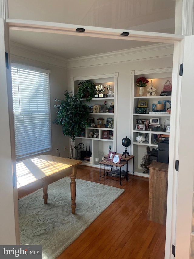 office featuring hardwood / wood-style flooring, ornamental molding, and built in shelves