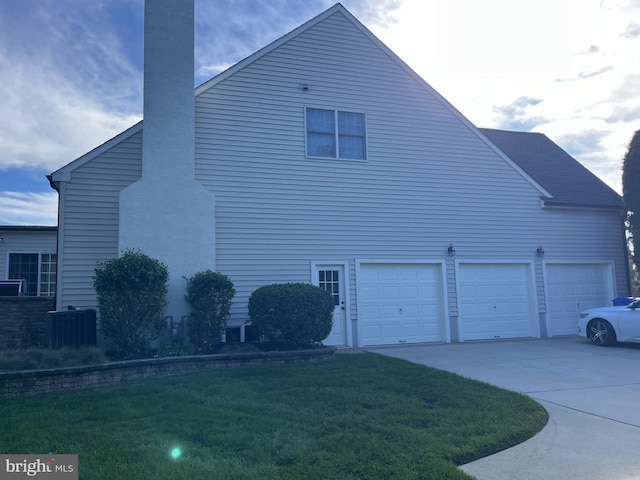 view of side of home featuring a garage, a yard, and central AC unit