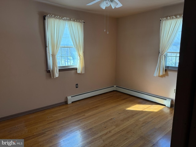 spare room with ceiling fan, wood-type flooring, plenty of natural light, and baseboard heating