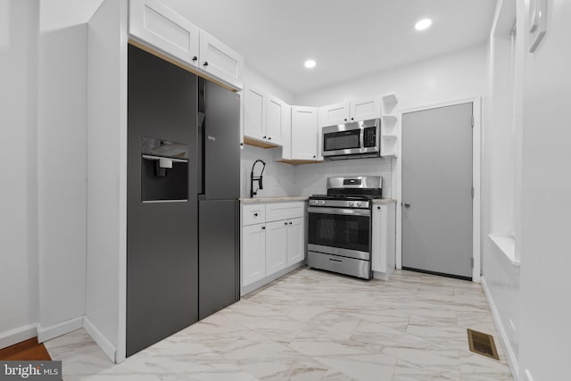 kitchen with backsplash, white cabinets, and appliances with stainless steel finishes