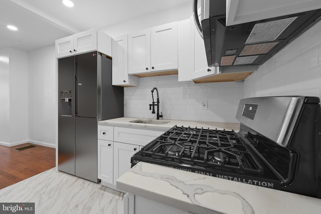 kitchen with white cabinetry, sink, black refrigerator with ice dispenser, and stainless steel gas range oven