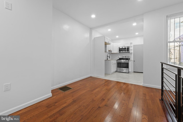 unfurnished living room featuring sink and light hardwood / wood-style floors