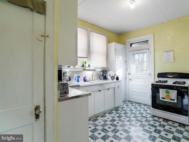 kitchen with white cabinetry, tasteful backsplash, sink, and range with gas cooktop