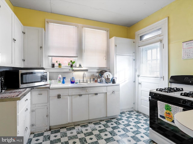 kitchen with white cabinetry, sink, backsplash, and gas range oven