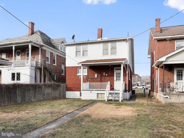 back of property featuring a yard and covered porch