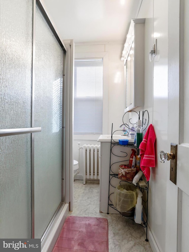 bathroom with a shower with door, radiator, and toilet