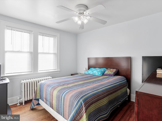 bedroom with radiator, dark wood-type flooring, and ceiling fan