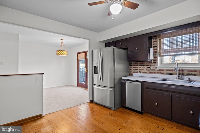 kitchen featuring sink, decorative light fixtures, dark brown cabinets, light hardwood / wood-style flooring, and stainless steel appliances