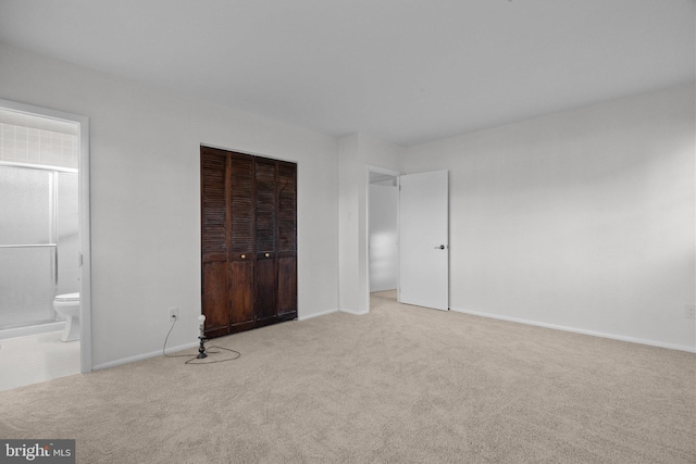 unfurnished bedroom featuring light carpet, connected bathroom, and a closet