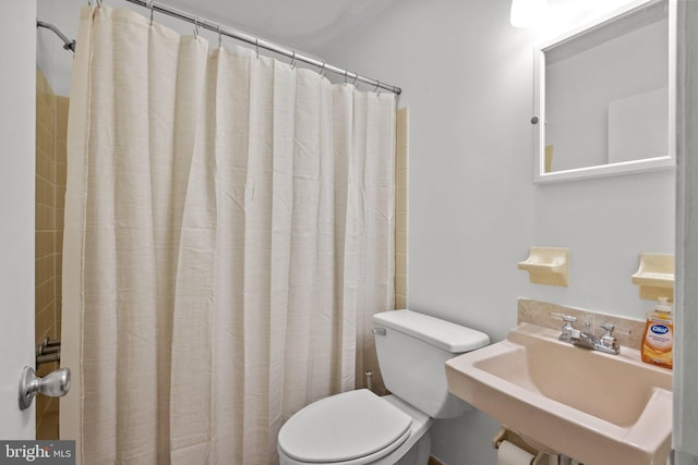 bathroom featuring a shower with curtain, toilet, and sink