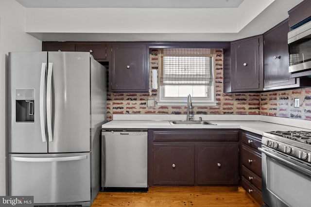 kitchen featuring sink, dark brown cabinets, stainless steel appliances, and light wood-type flooring