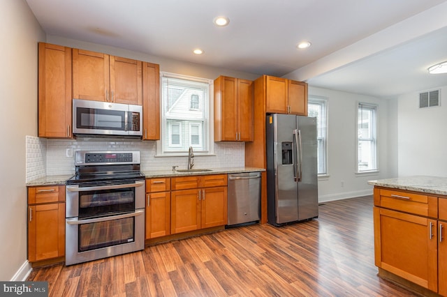 kitchen with light stone counters, stainless steel appliances, dark hardwood / wood-style flooring, and sink