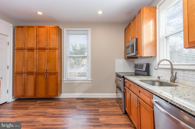 kitchen with sink, light stone counters, tasteful backsplash, appliances with stainless steel finishes, and dark hardwood / wood-style floors