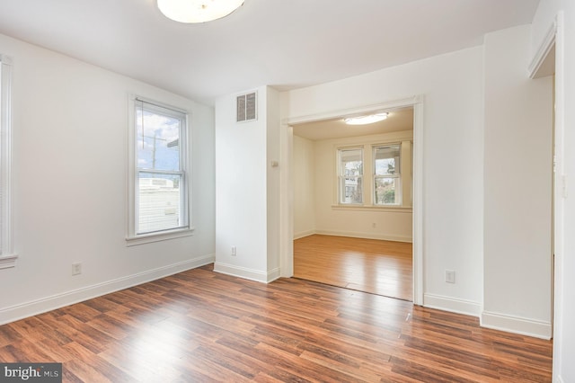 spare room featuring dark hardwood / wood-style flooring and a wealth of natural light