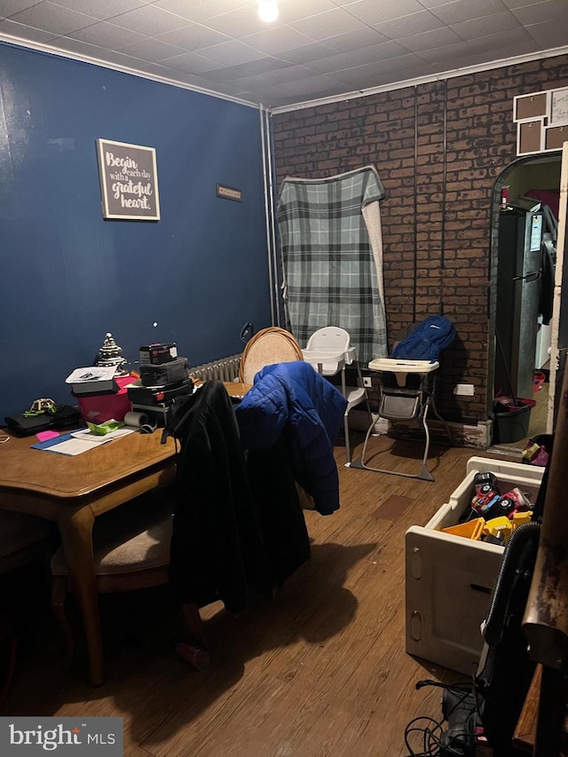 bedroom featuring brick wall, ornamental molding, and hardwood / wood-style floors