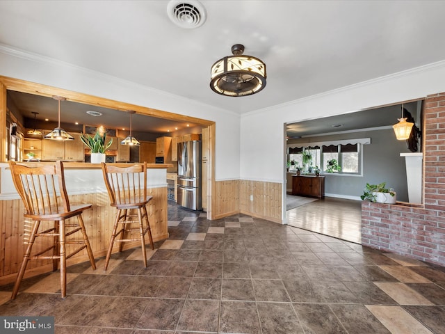 interior space featuring crown molding, stainless steel fridge, and decorative light fixtures