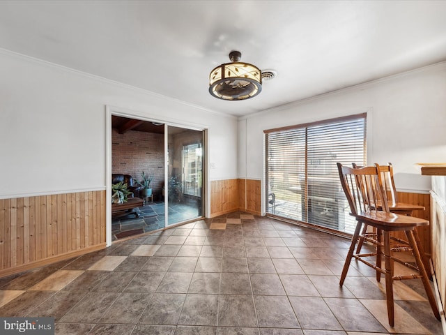 unfurnished dining area featuring tile patterned flooring, crown molding, and wooden walls