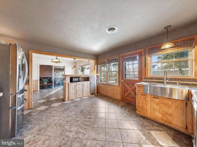 kitchen featuring sink, a healthy amount of sunlight, pendant lighting, and stainless steel fridge