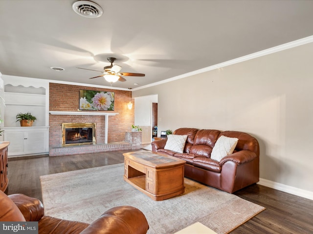 living room featuring dark hardwood / wood-style flooring, a brick fireplace, built in shelves, and ornamental molding