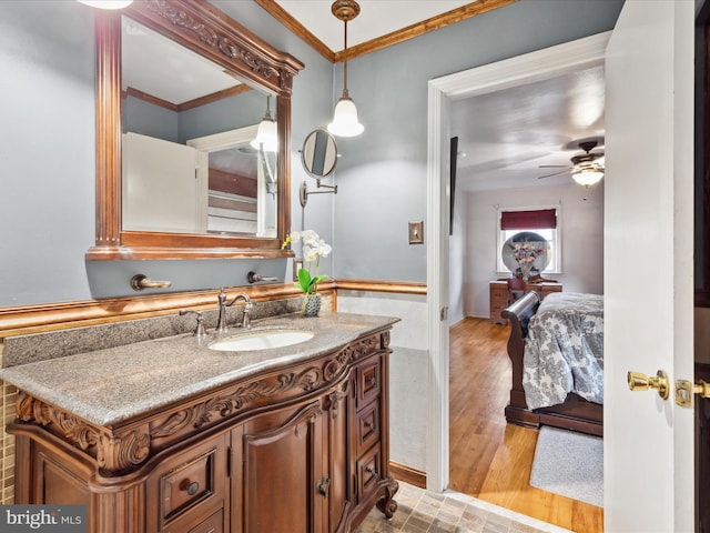 bathroom with crown molding, ceiling fan, vanity, and wood-type flooring