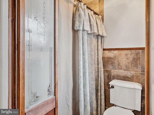 bathroom with tile walls, toilet, and a shower with shower curtain