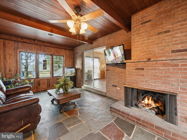 living room with beam ceiling, wood ceiling, wooden walls, ceiling fan, and a fireplace