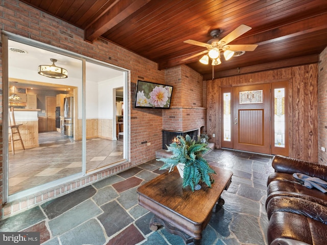 living room featuring wood ceiling, beam ceiling, wooden walls, a fireplace, and brick wall