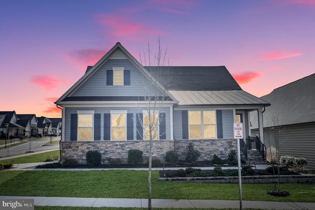 view of front of home featuring stone siding, a front yard, a standing seam roof, and metal roof