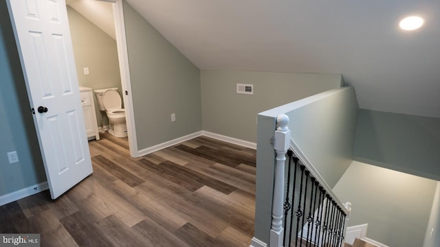 stairway with vaulted ceiling and hardwood / wood-style floors