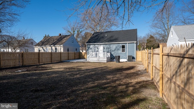 back of house with central AC, a wooden deck, and a lawn