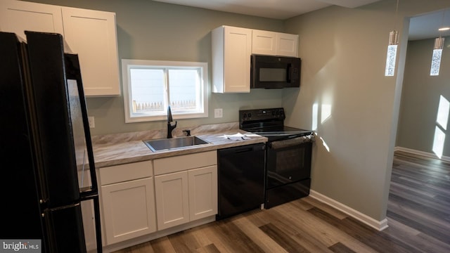 kitchen featuring sink, hanging light fixtures, wood-type flooring, black appliances, and white cabinets