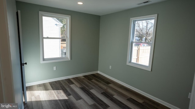 unfurnished room featuring dark wood-type flooring and a healthy amount of sunlight