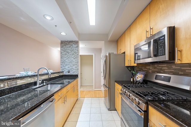 kitchen featuring tasteful backsplash, sink, dark stone counters, and appliances with stainless steel finishes