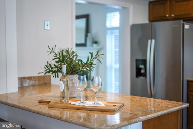 kitchen featuring stainless steel fridge, light stone countertops, and kitchen peninsula