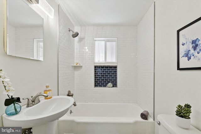 full bathroom featuring sink, tiled shower / bath combo, and toilet